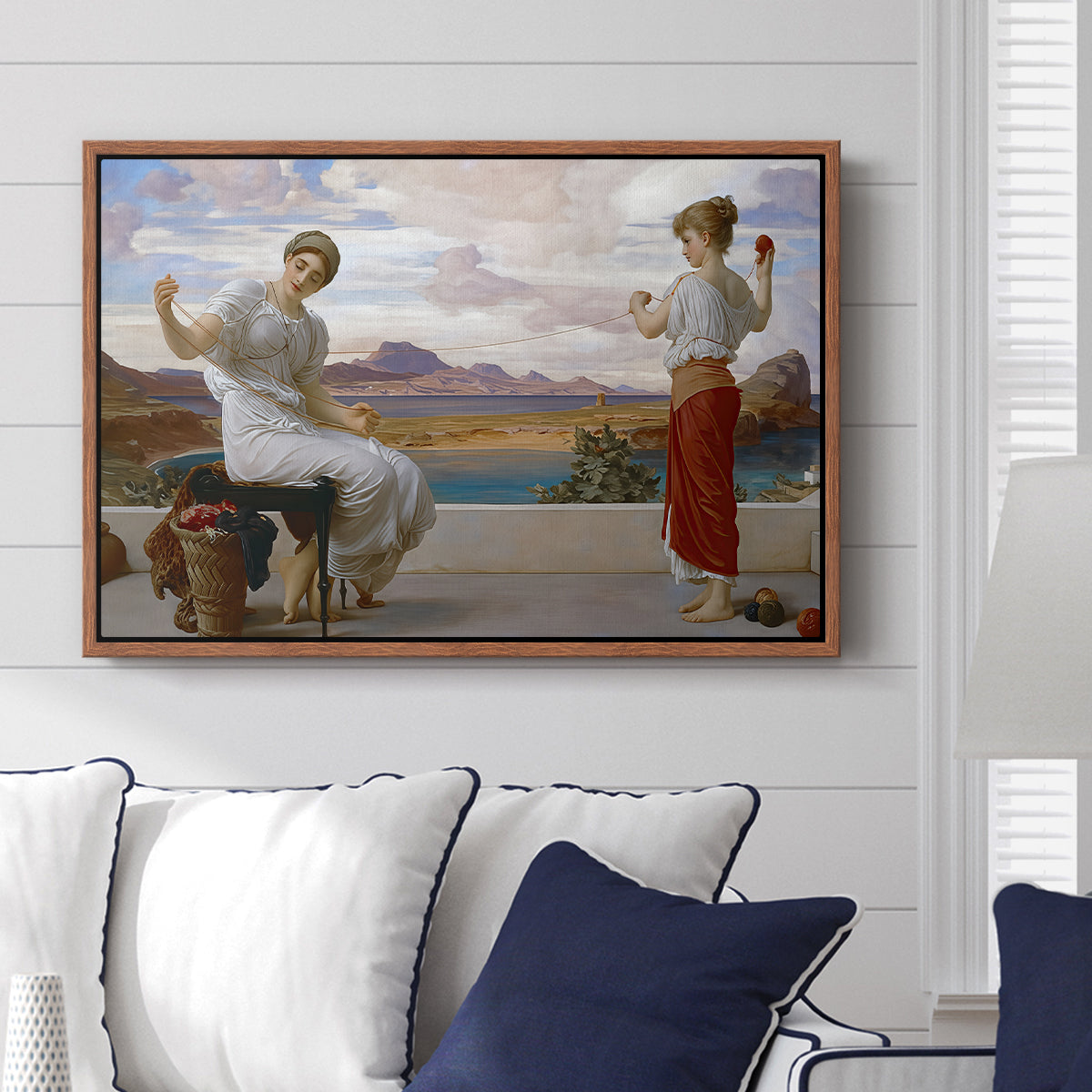 Winding the Skein, c. 1878 by Frederic Leighton displayed above a sofa in a living room in a walnut floater frame, featuring two women engaged in textile work with draped garments.