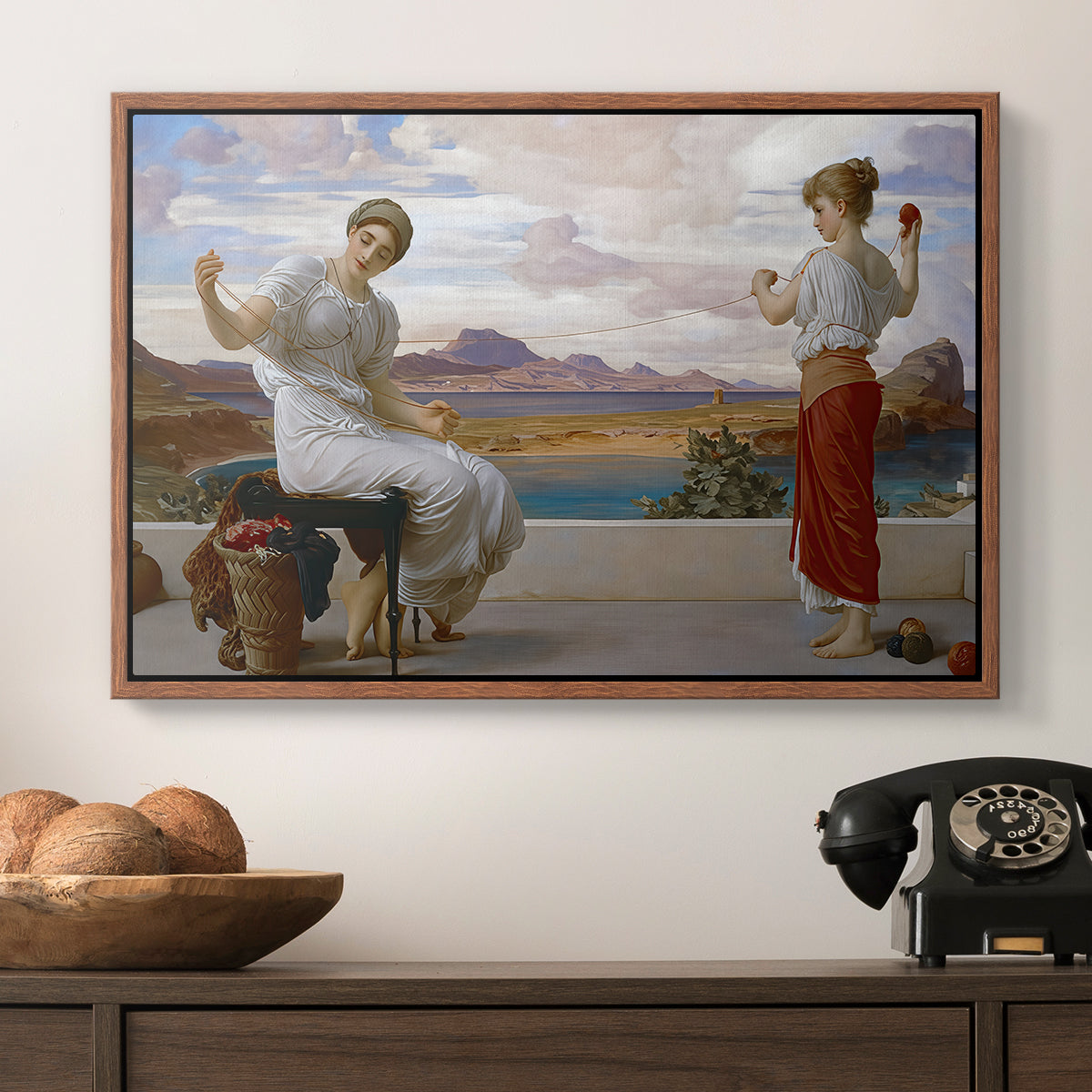 Winding the Skein, c. 1878 by Frederic Leighton in a walnut floater framed canvas displayed above a console table in a hallway, featuring an elegant composition of women performing domestic task.