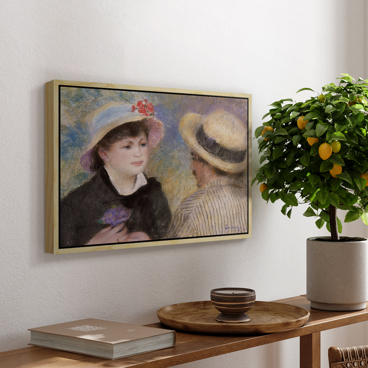 Boating Couple (Aline Charigot and Renoir), c. 1881 by Pierre-Auguste Renoir, presented in a natural wood floater framed canvas featuring a close-up of a couple seated together outdoors with hats and soft sunlight, displayed above a hallway console table.