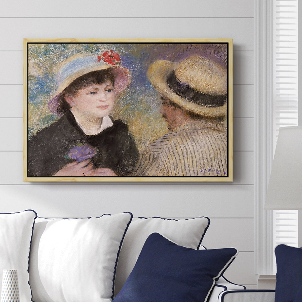 Boating Couple (Aline Charigot and Renoir), c. 1881 by Pierre-Auguste Renoir displayed above a sofa in a living room in a natural wood floater frame, featuring an intimate portrait of man and woman sitting side by side in outdoor setting.