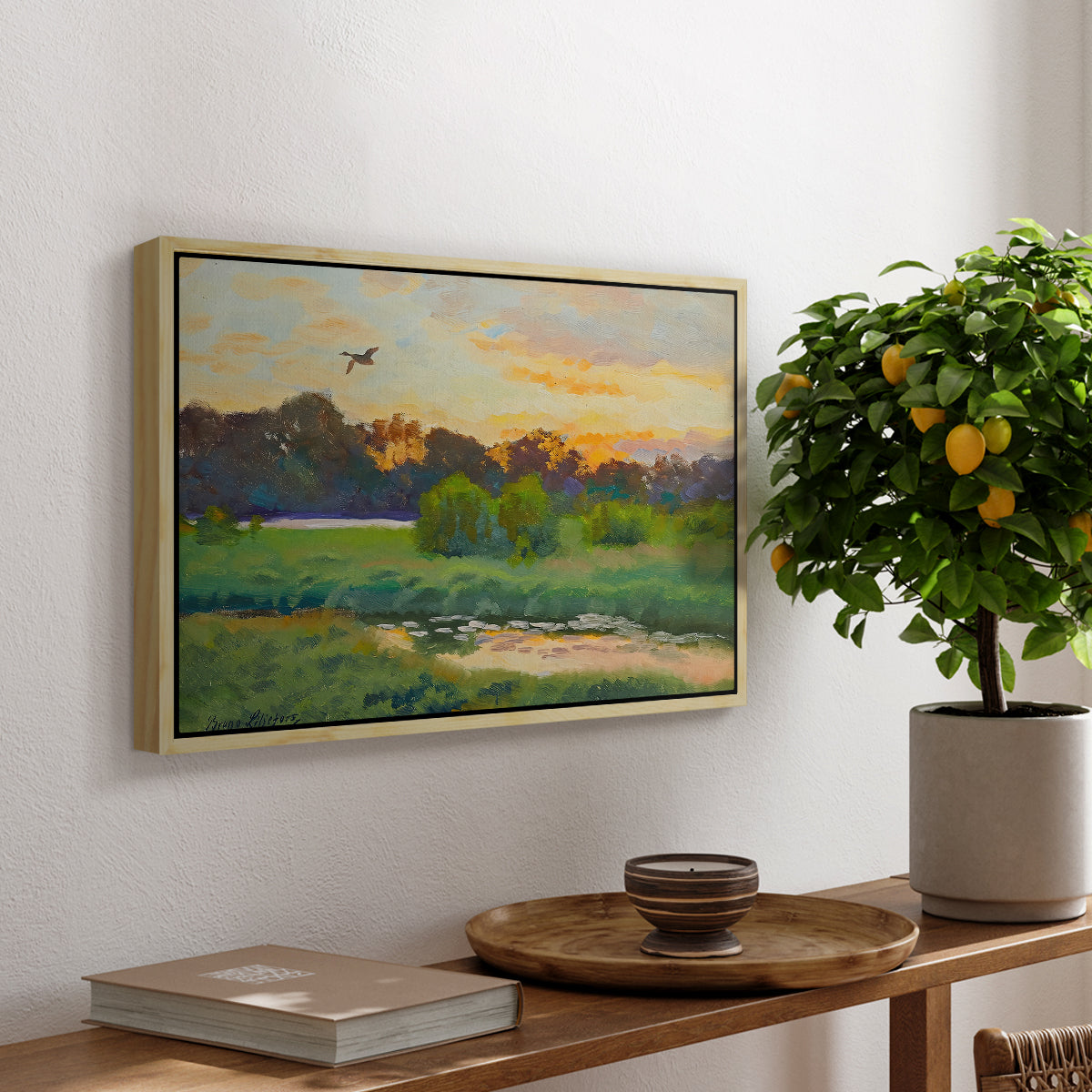 Flying Duck at Sunset, 1924 by Bruno Liljefors, presented in a natural wood floater framed canvas featuring a wild duck flying over a sunset marsh with trees, displayed above a hallway console table.