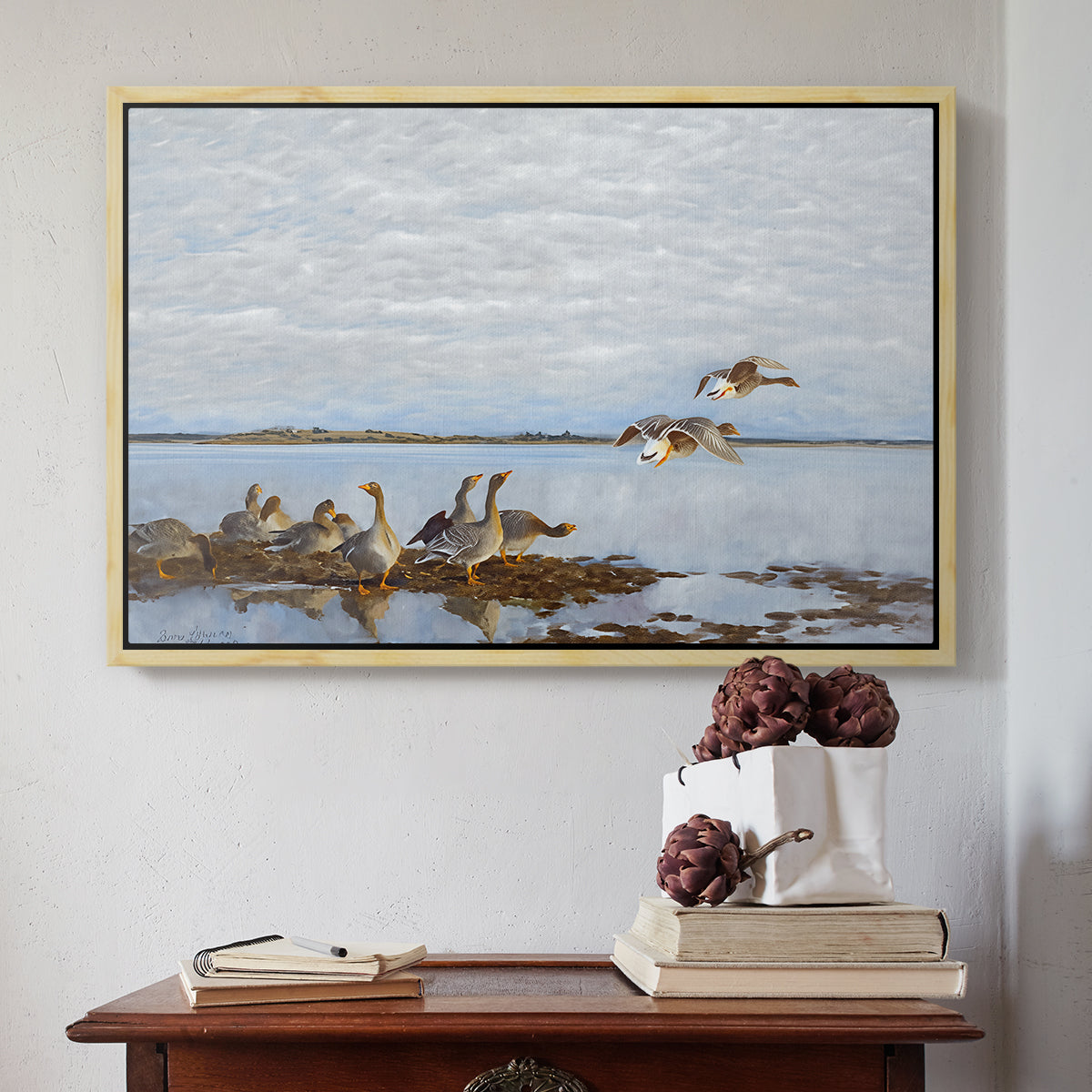 Natural wood floater framed canvas featuring Greylag Geese (Grågäss), 1922 by Bruno Liljefors above an entryway table in a minimalist foyer.