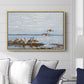 Greylag Geese (Grågäss), 1922 by Bruno Liljefors displayed above a sofa in a living room in a natural wood floater frame, featuring birds standing and resting along shoreline with soft grass and water.