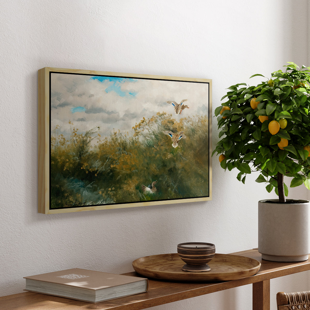 Wild Ducks (Grasänder), 1890 by Bruno Liljefors, presented in a natural wood floater framed canvas featuring ducks moving through grassy wetland near water's edge, displayed above a hallway console table.