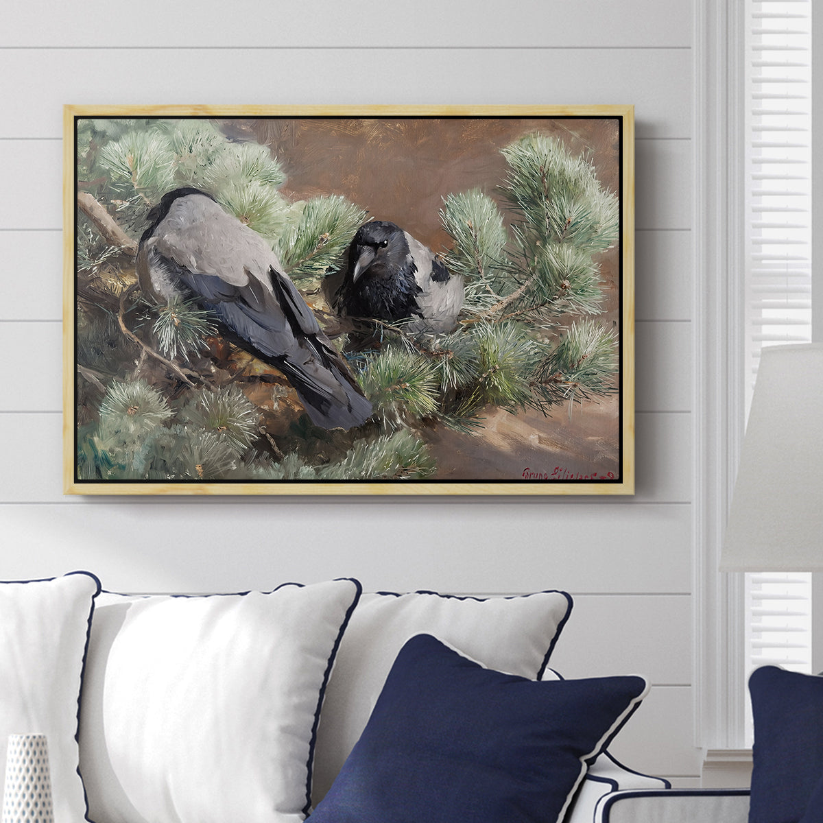 Hooded Crows (Kråkor), 1891 by Bruno Liljefors displayed above a sofa in a living room in a natural wood floater frame, featuring birds standing alert in natural field environment.