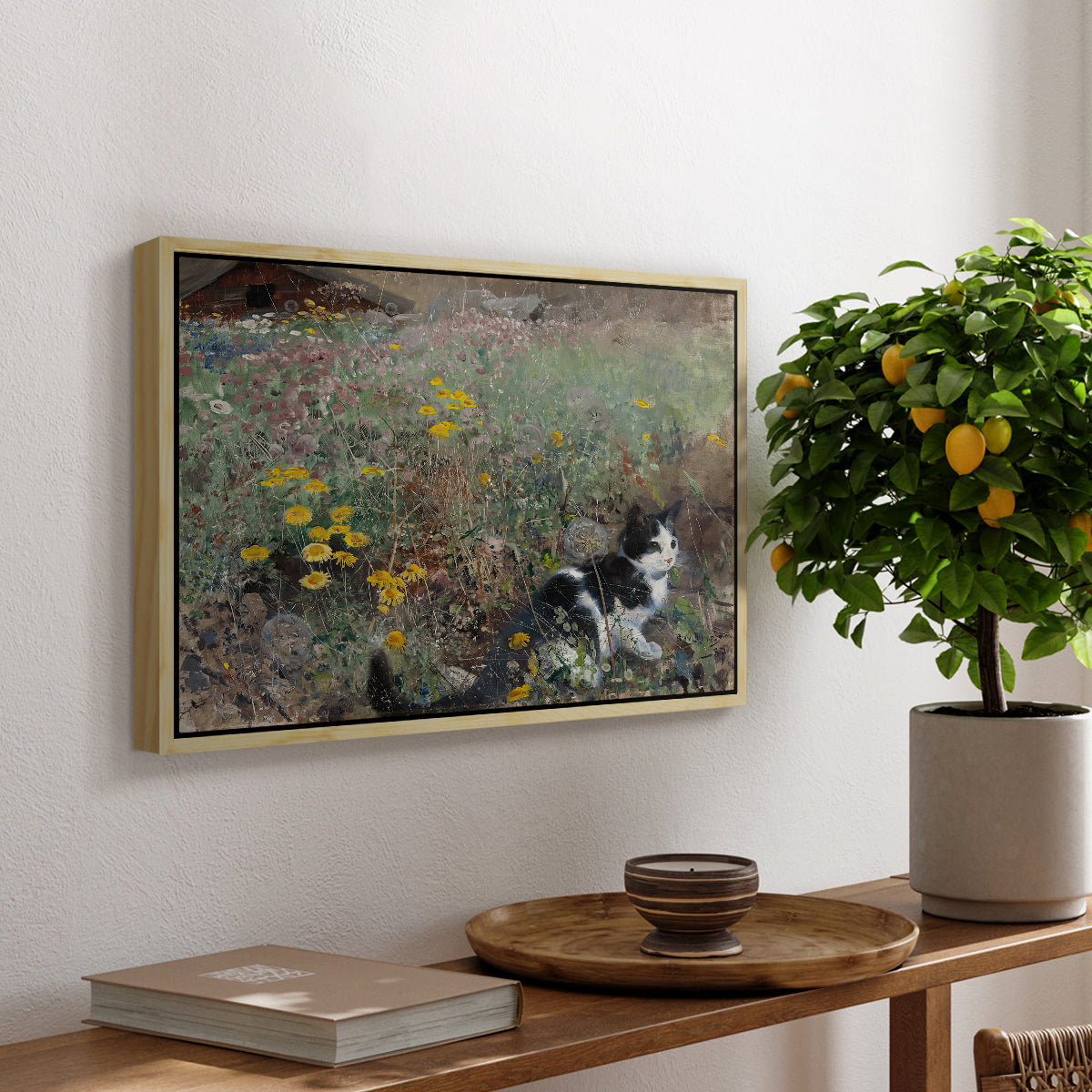 Cat on a Flowery Meadow, 1887 by Bruno Liljefors, presented in a natural wood floater framed canvas featuring a cat crouching in a meadow filled with wildflowers and greenery, displayed above a hallway console table.