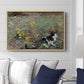 Cat on a Flowery Meadow, 1887 by Bruno Liljefors displayed above a sofa in a living room in a natural wood floater frame, featuring a small cat resting among colorful flowers in grassy field.