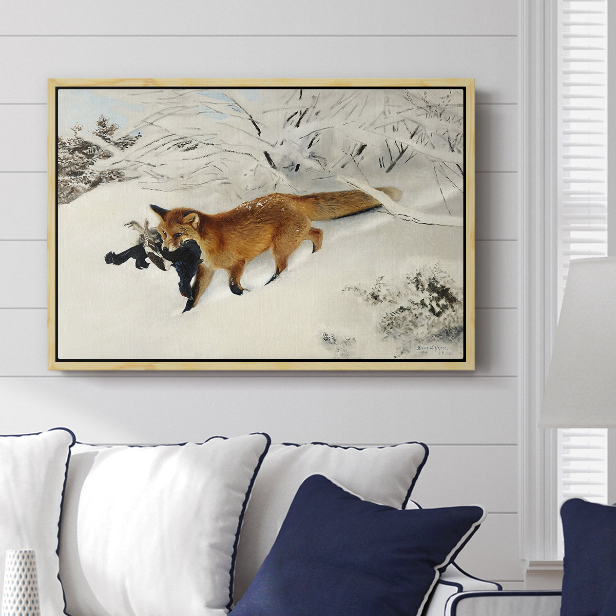 Fox in Snow Landscape, 1900 by Bruno Liljefors displayed above a sofa in a living room in a natural wood floater frame, featuring a wildlife scene of fox moving swiftly through winter terrain.