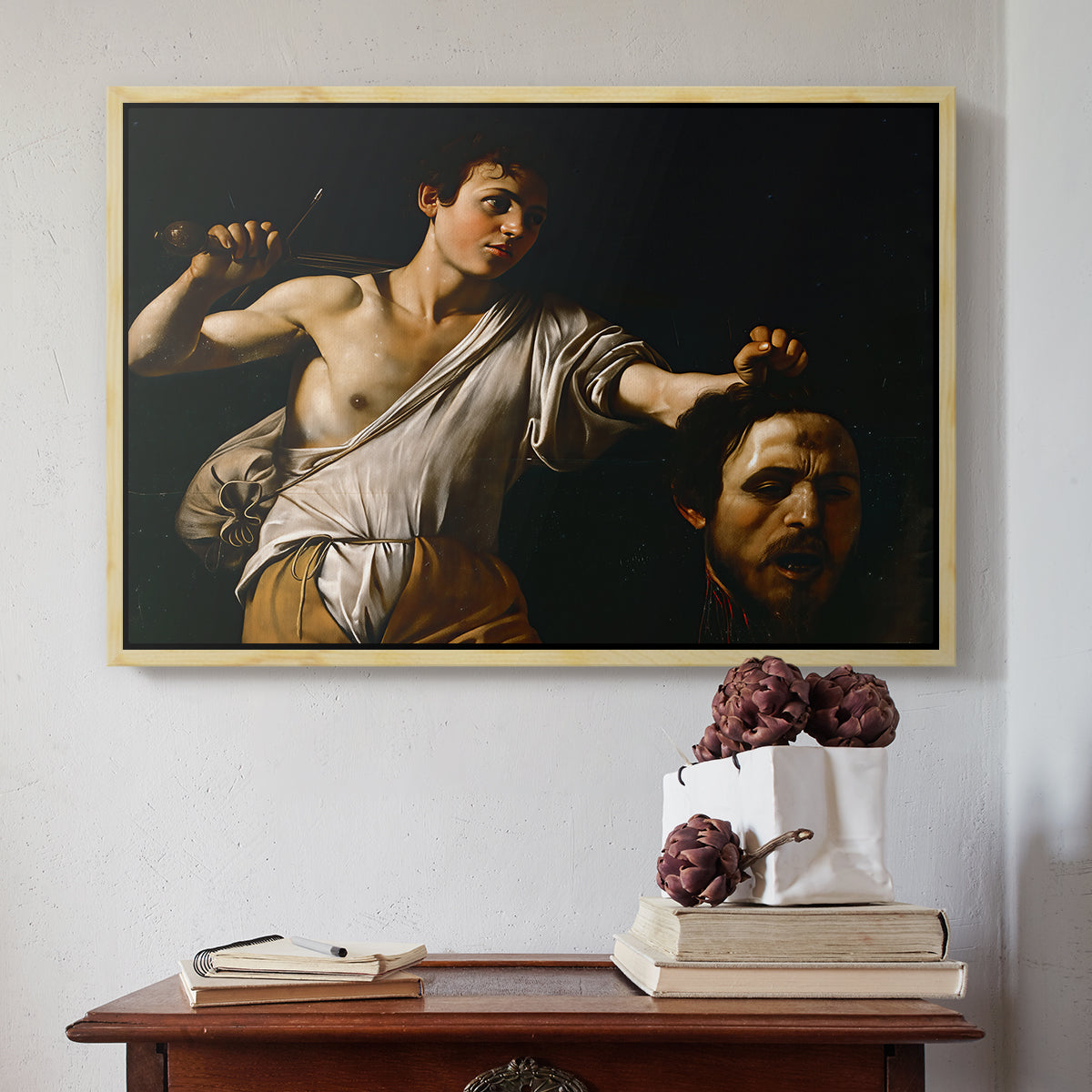 Natural wood floater framed canvas featuring David with the Head of Goliath (Vienna Version), c. 1607 by Caravaggio above an entryway table in a minimalist foyer.