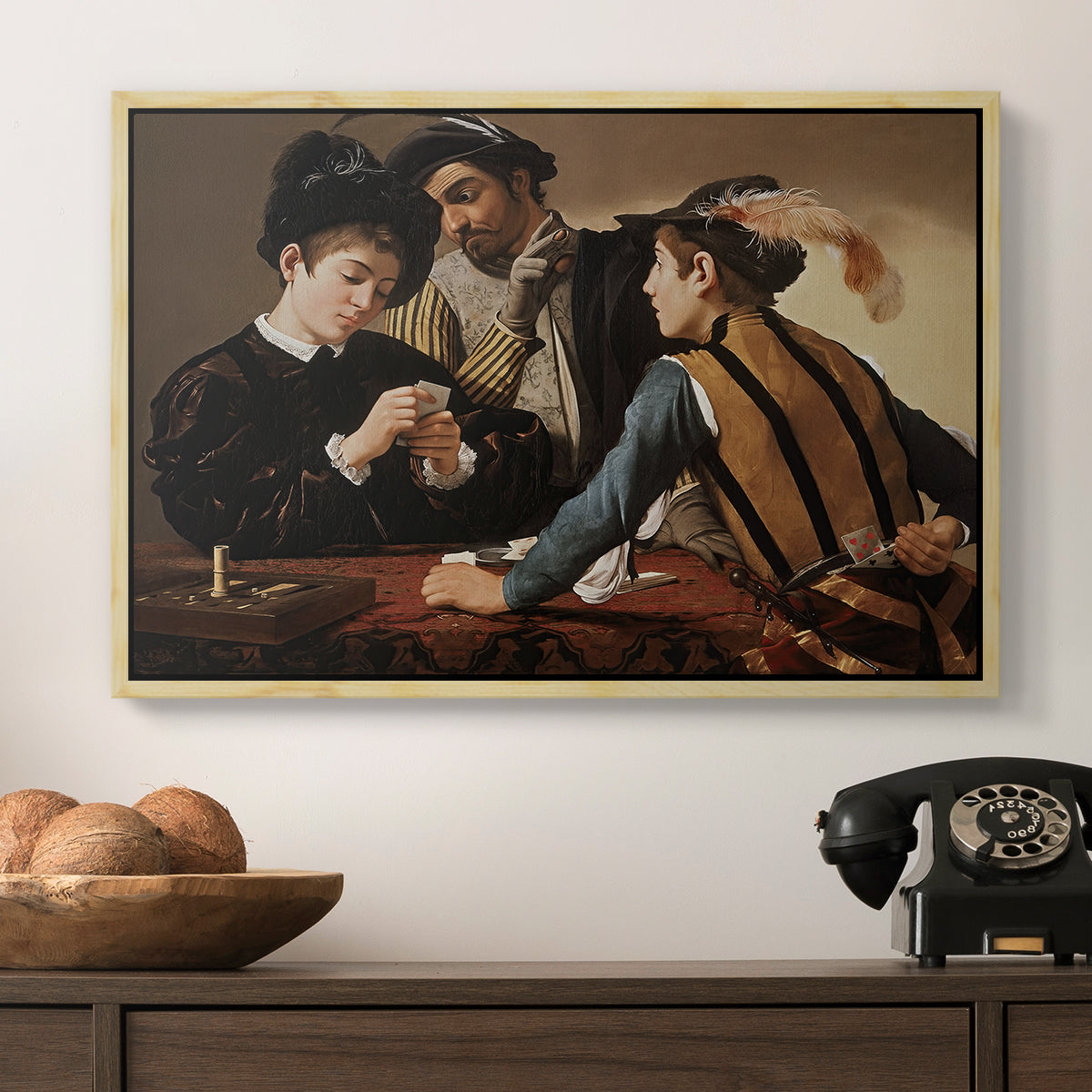 The Cardsharps, c. 1594 by Caravaggio in a natural wood floater framed canvas displayed above a console table in a hallway, featuring a dramatic interior scene of gambling and trickery among figures.