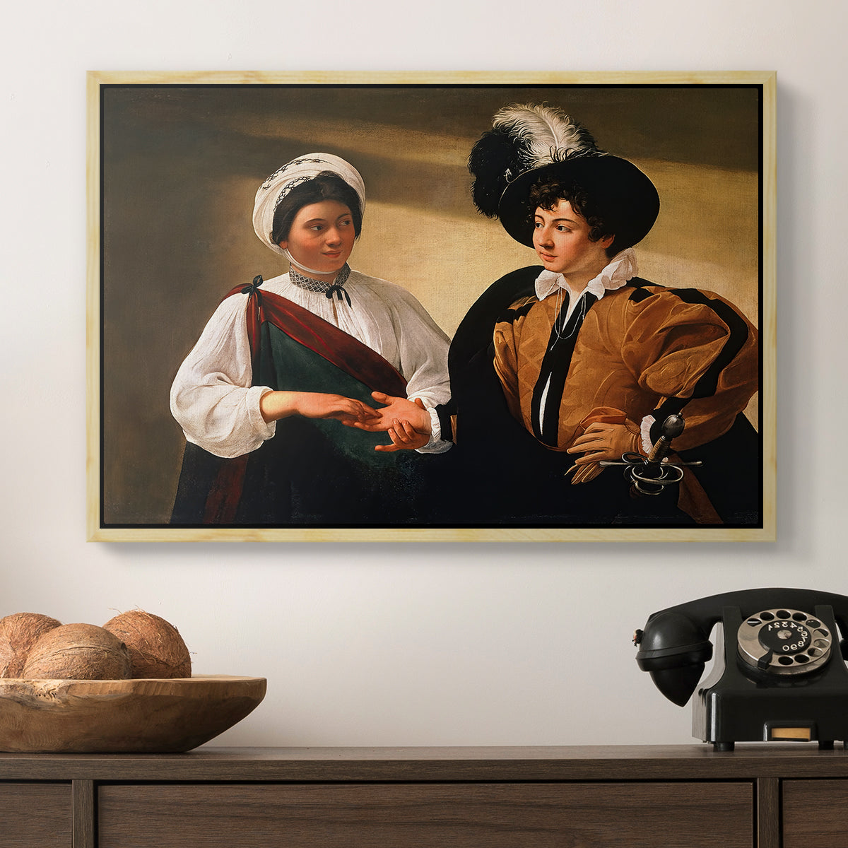 The Fortune Teller (Louvre Version), c. 1595 by Caravaggio in a natural wood floater framed canvas displayed above a console table in a hallway, featuring two figures engaged in fortune telling with hidden deception.