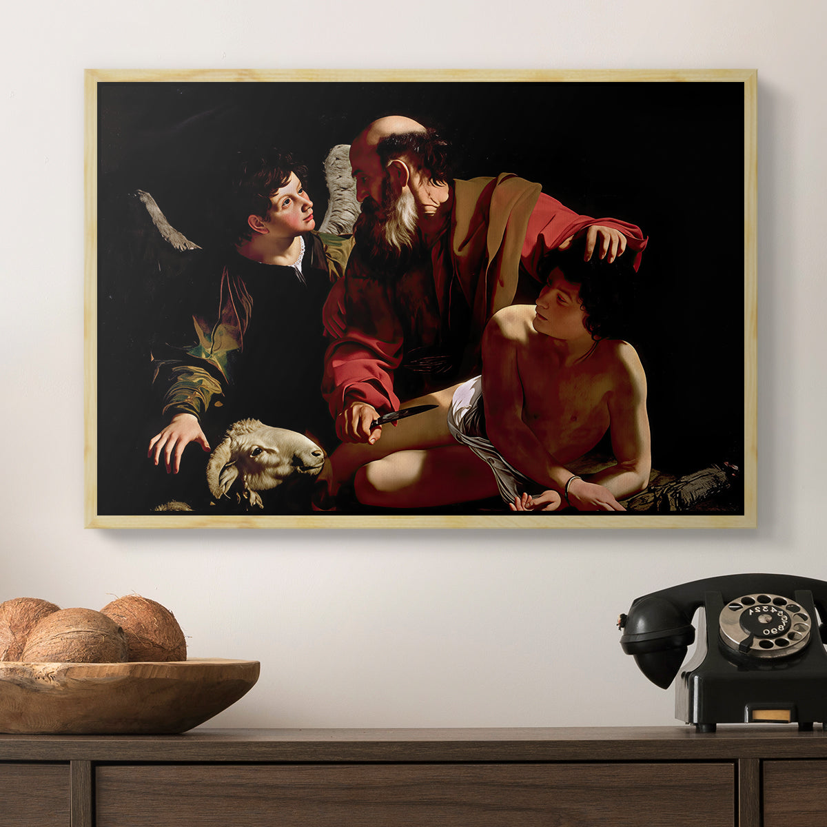 The Sacrifice of Isaac (Uffizi Version), c. 1603 by Caravaggio in a natural wood floater framed canvas displayed above a console table in a hallway, featuring an intense religious narrative with figures in close physical struggle.