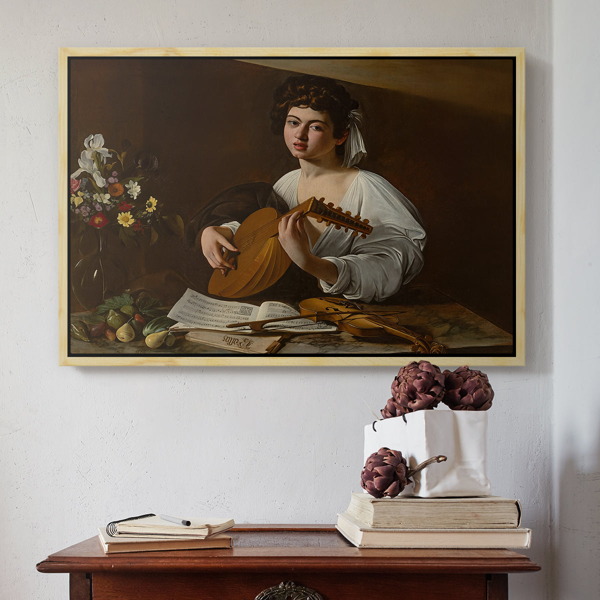 Natural wood floater framed canvas featuring The Lute Player (Hermitage Version), c. 1596 by Caravaggio above an entryway table in a minimalist foyer.