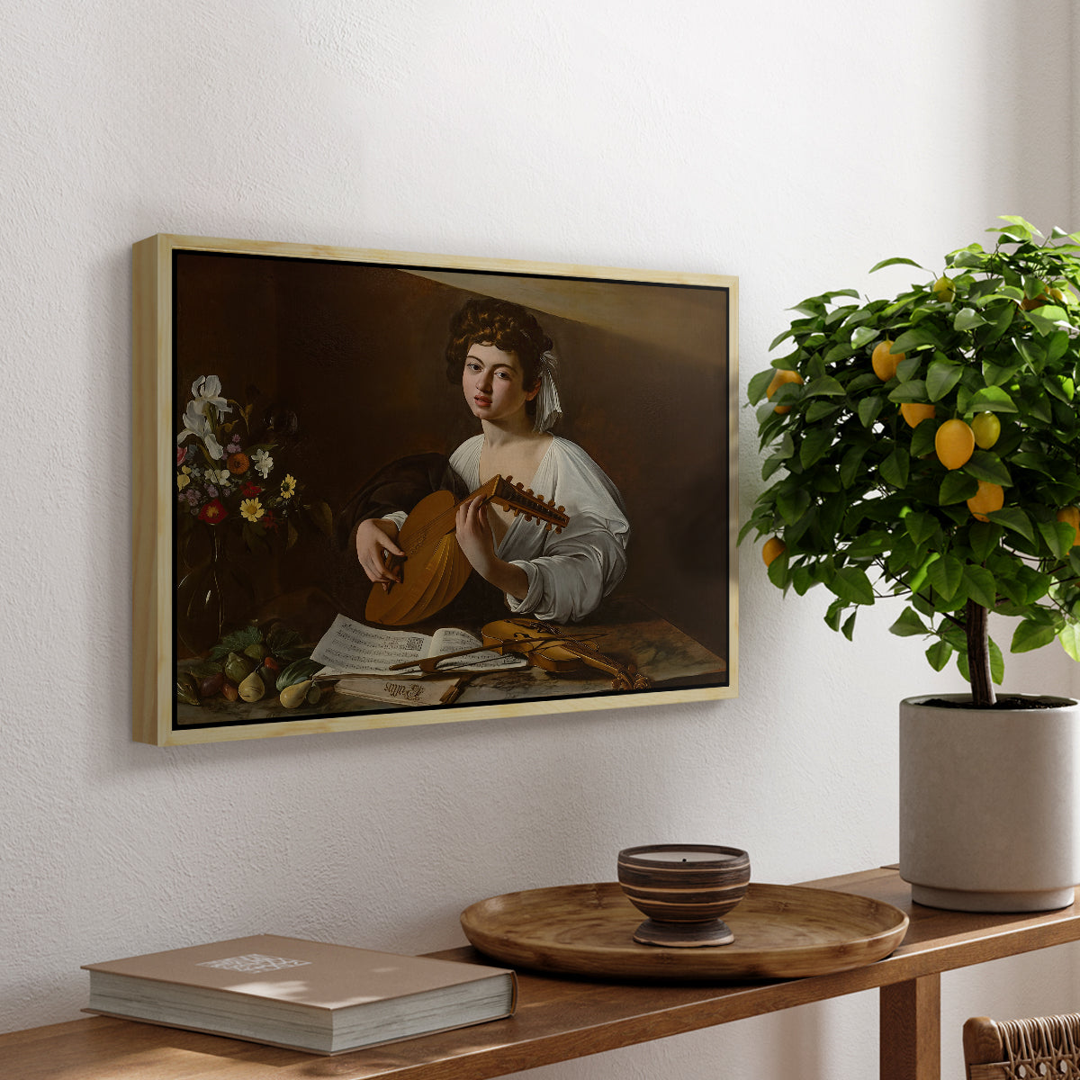 The Lute Player (Hermitage Version), c. 1596 by Caravaggio, presented in a natural wood floater framed canvas featuring a young musician playing lute beside table with fruit and sheet music, displayed above a hallway console table.