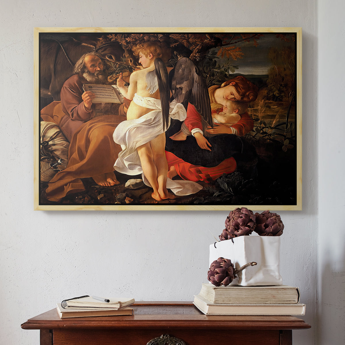 Natural wood floater framed canvas featuring Rest on the Flight into Egypt, c. 1597 by Caravaggio above an entryway table in a minimalist foyer.