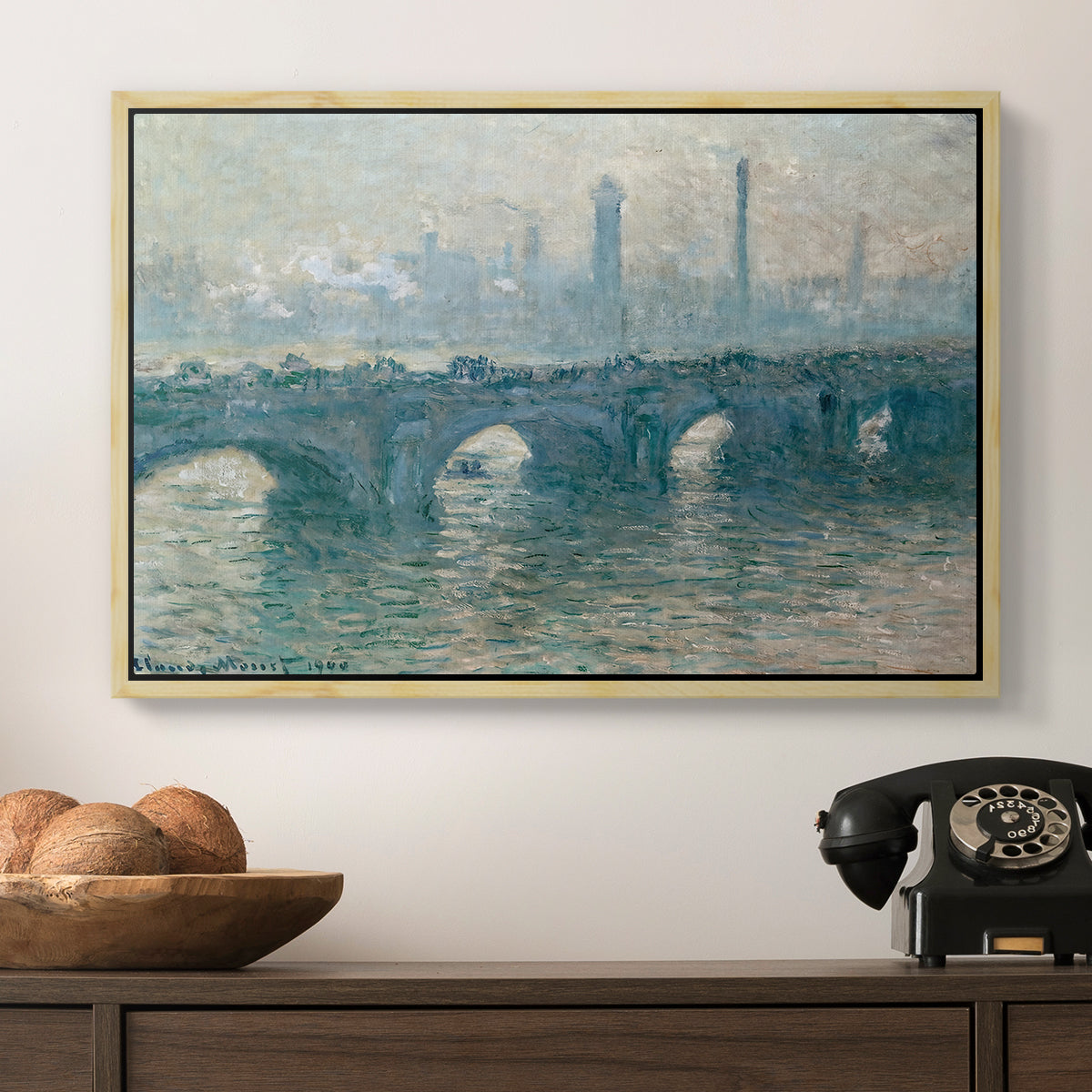 Waterloo Bridge, Gray Weather, 1900 by Claude Monet in a natural wood floater framed canvas displayed above a console table in a hallway, featuring an atmospheric urban landscape with misty light and reflections.