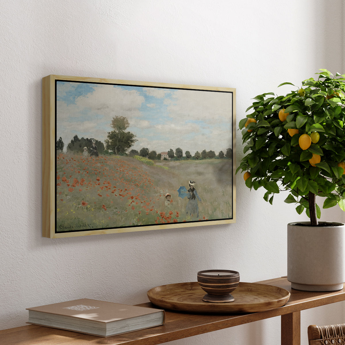 The Poppy Field near Argenteuil, 1873 by Claude Monet, presented in a natural wood floater framed canvas featuring a field of red poppies with figures walking across rolling landscape, displayed above a hallway console table.