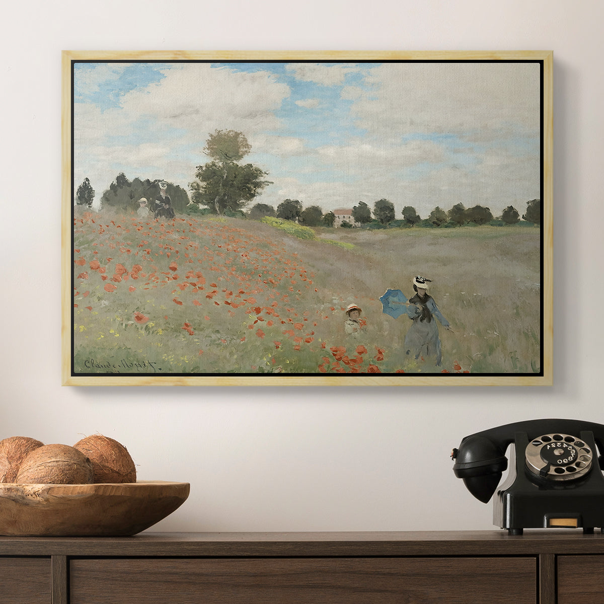 The Poppy Field near Argenteuil, 1873 by Claude Monet in a natural wood floater framed canvas displayed above a console table in a hallway, featuring a rural landscape with scattered figures among blooming flowers.