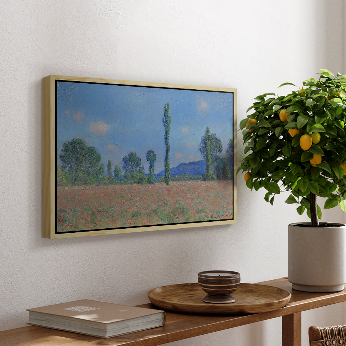 Poppy Field (Giverny), 1890-1891 by Claude Monet, presented in a natural wood floater framed canvas featuring an expansive field of red poppies with tall trees under blue sky, displayed above a hallway console table.