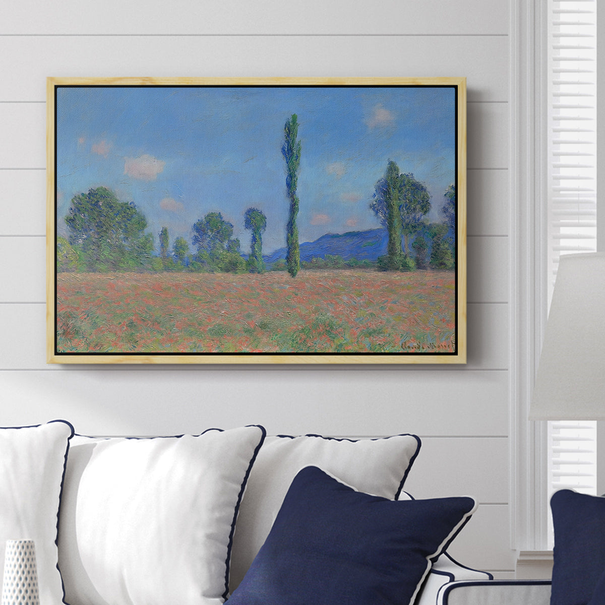 Poppy Field (Giverny), 1890-1891 by Claude Monet displayed above a sofa in a living room in a natural wood floater frame, featuring an impressionist landscape of blooming poppies in countryside.
