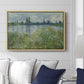 Banks of the Seine, Vétheuil, 1880 by Claude Monet displayed above a sofa in a living room in a natural wood floater frame, featuring an impressionist view of Seine with reflections and greenery.