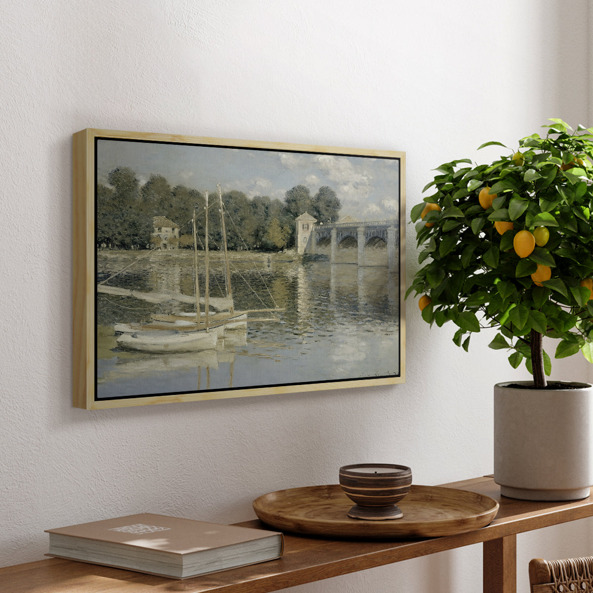 The Bridge at Argenteuil, 1874 by Claude Monet, presented in a natural wood floater framed canvas featuring a bridge spanning river with sailboats and reflections in water, displayed above a hallway console table.