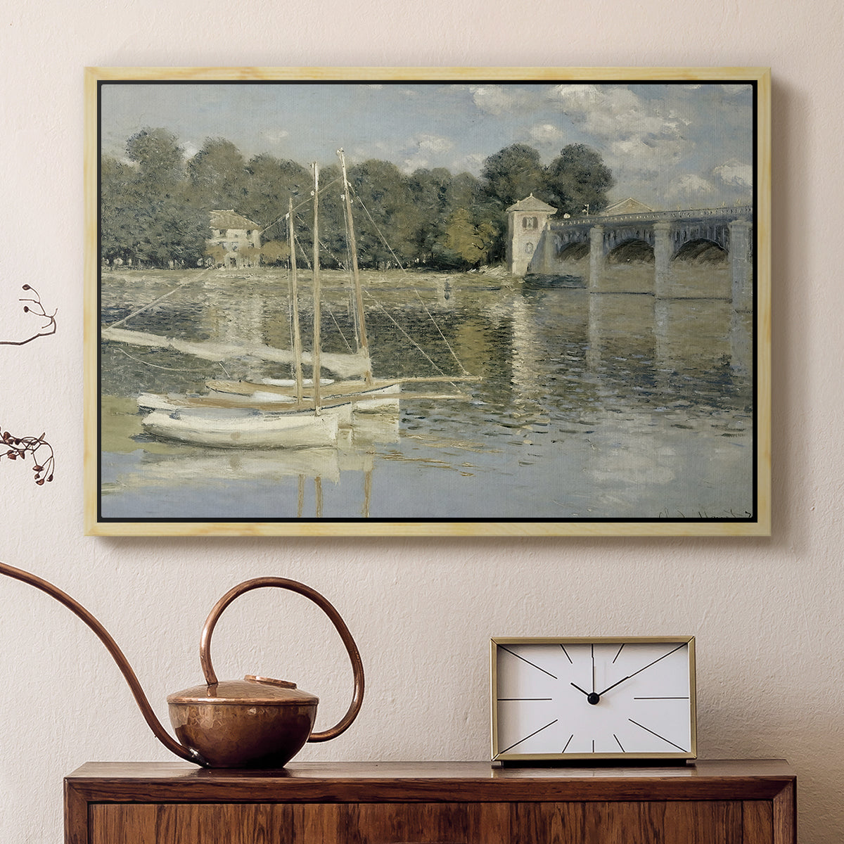 Natural wood floater framed canvas featuring a bright landscape featuring bridge and sailboats on calm water, displayed above a cabinet in a soft-toned living room.