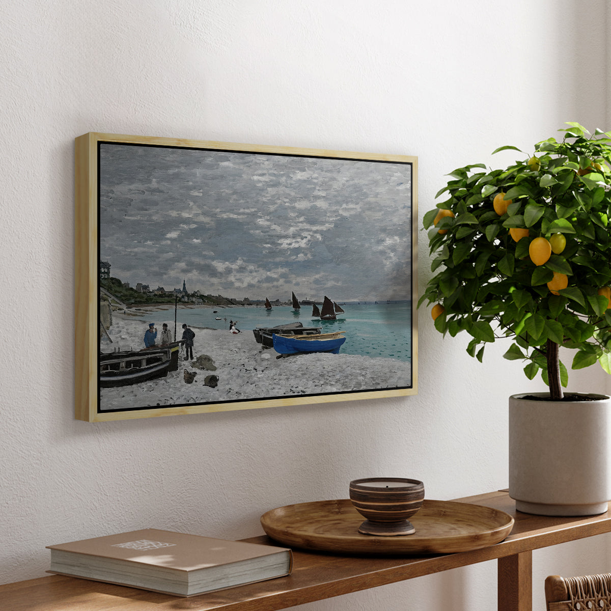 The Beach at Sainte-Adresse, 1867 by Claude Monet, presented in a natural wood floater framed canvas featuring a seaside promenade with figures, flags, and boats along the coast, displayed above a hallway console table.