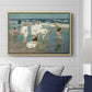 A Holiday, c. 1915 by Edward Henry Potthast displayed above a sofa in a living room in a natural wood floater frame, featuring a beach scene with figures bathing and standing in waves under bright sky.