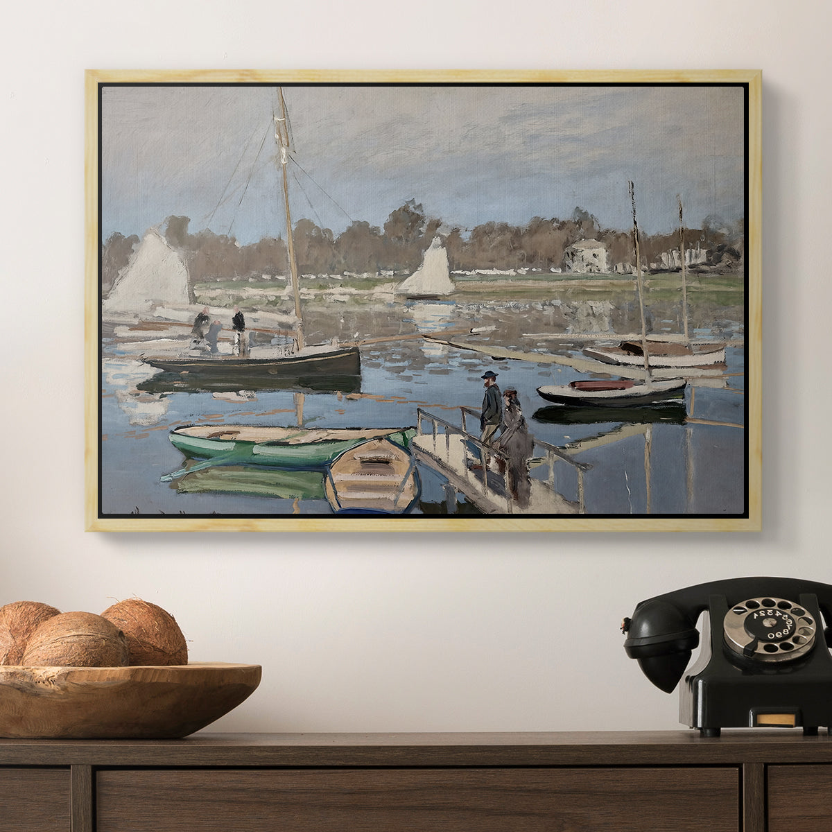 The Basin at Argenteuil, 1874 by Claude Monet in a natural wood floater framed canvas displayed above a console table in a hallway, featuring a tranquil river setting with sailboats and shoreline.