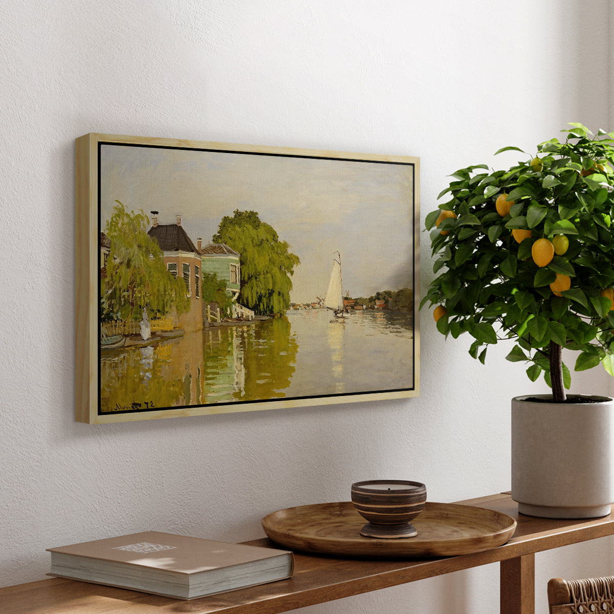 Houses on the Achterzaan, 1871 by Claude Monet, presented in a natural wood floater framed canvas featuring colorful houses reflected in calm river surrounded by greenery, displayed above a hallway console table.