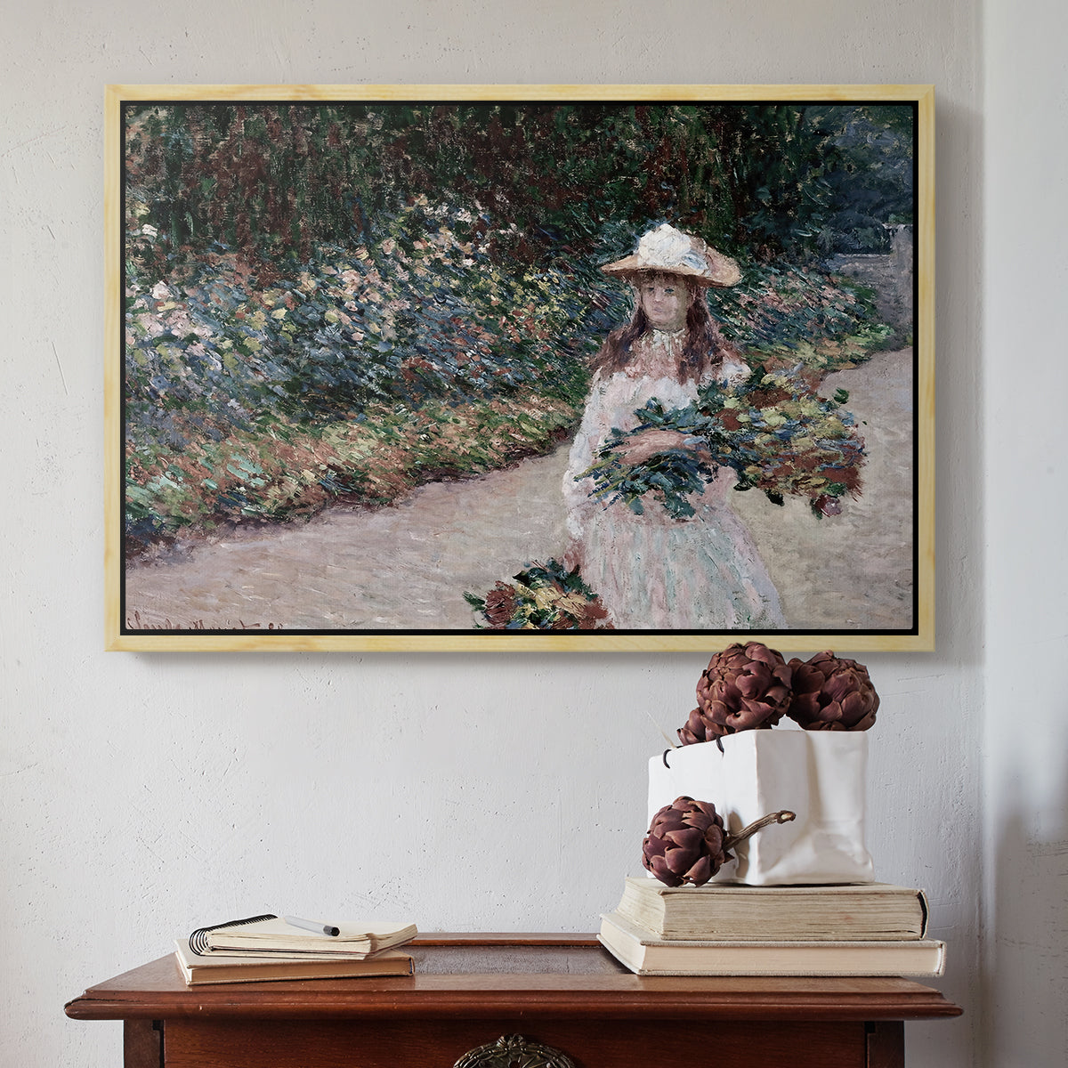 Natural wood floater framed canvas featuring Young Girl in the Garden at Giverny, 1888 by Claude Monet above an entryway table in a minimalist foyer.