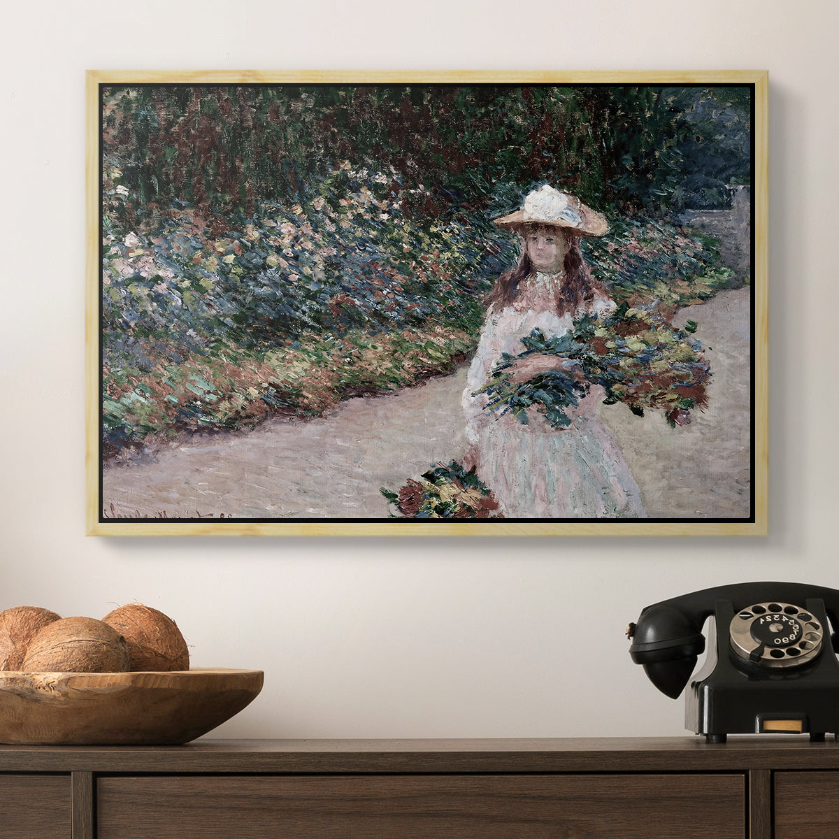 Young Girl in the Garden at Giverny, 1888 by Claude Monet in a natural wood floater framed canvas displayed above a console table in a hallway, featuring a tranquil outdoor portrait of girl in floral setting.