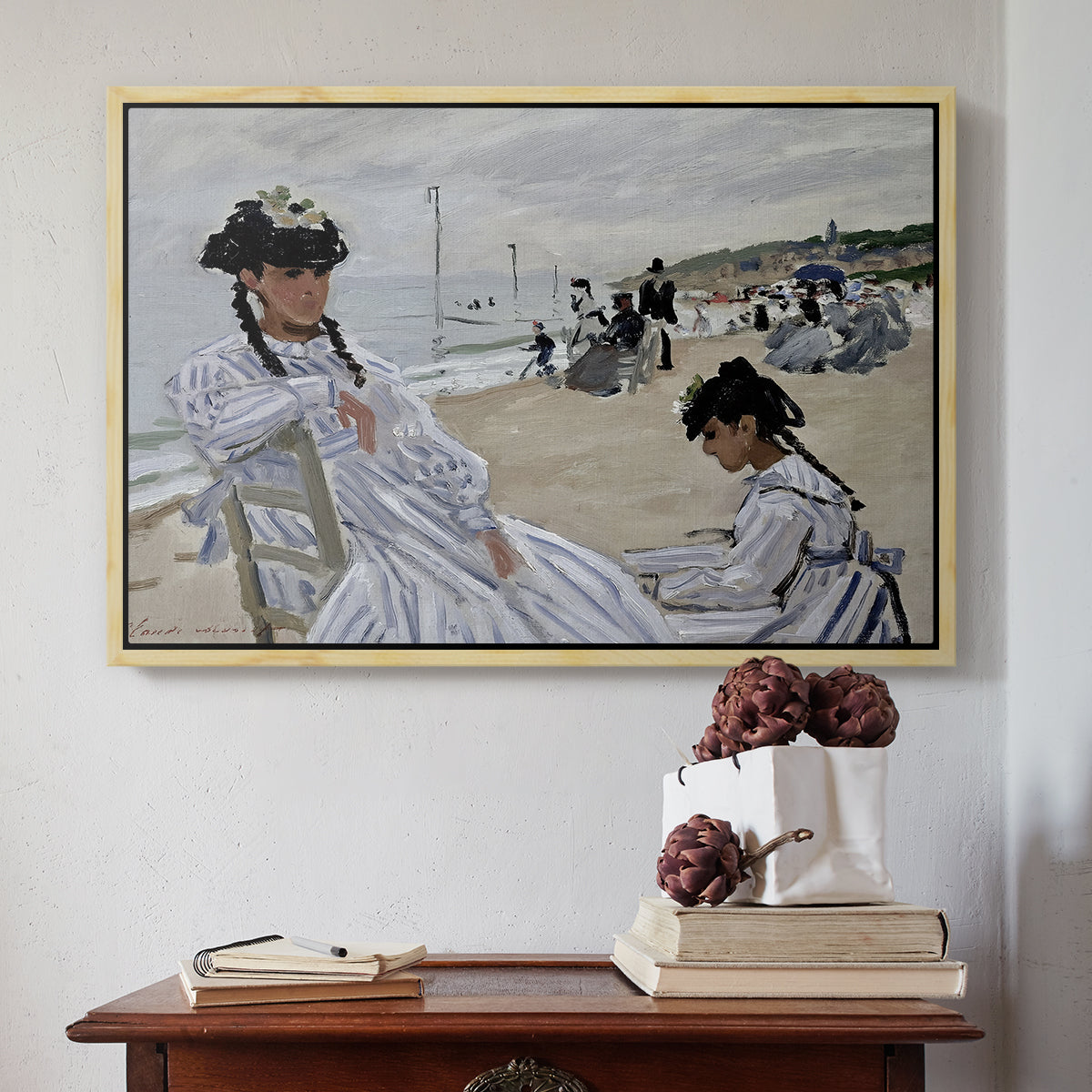 Natural wood floater framed canvas featuring On the Beach at Trouville, 1870 by Claude Monet above an entryway table in a minimalist foyer.