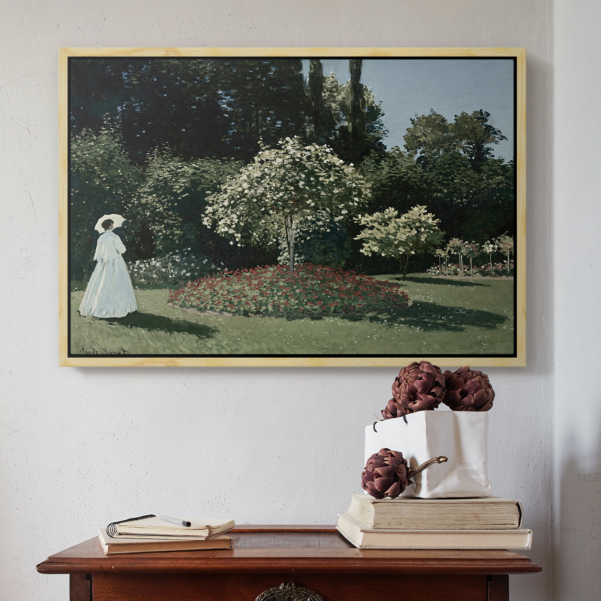 Natural wood floater framed canvas featuring Woman in the Garden, Sainte-Adresse, 1867 by Claude Monet above an entryway table in a minimalist foyer.
