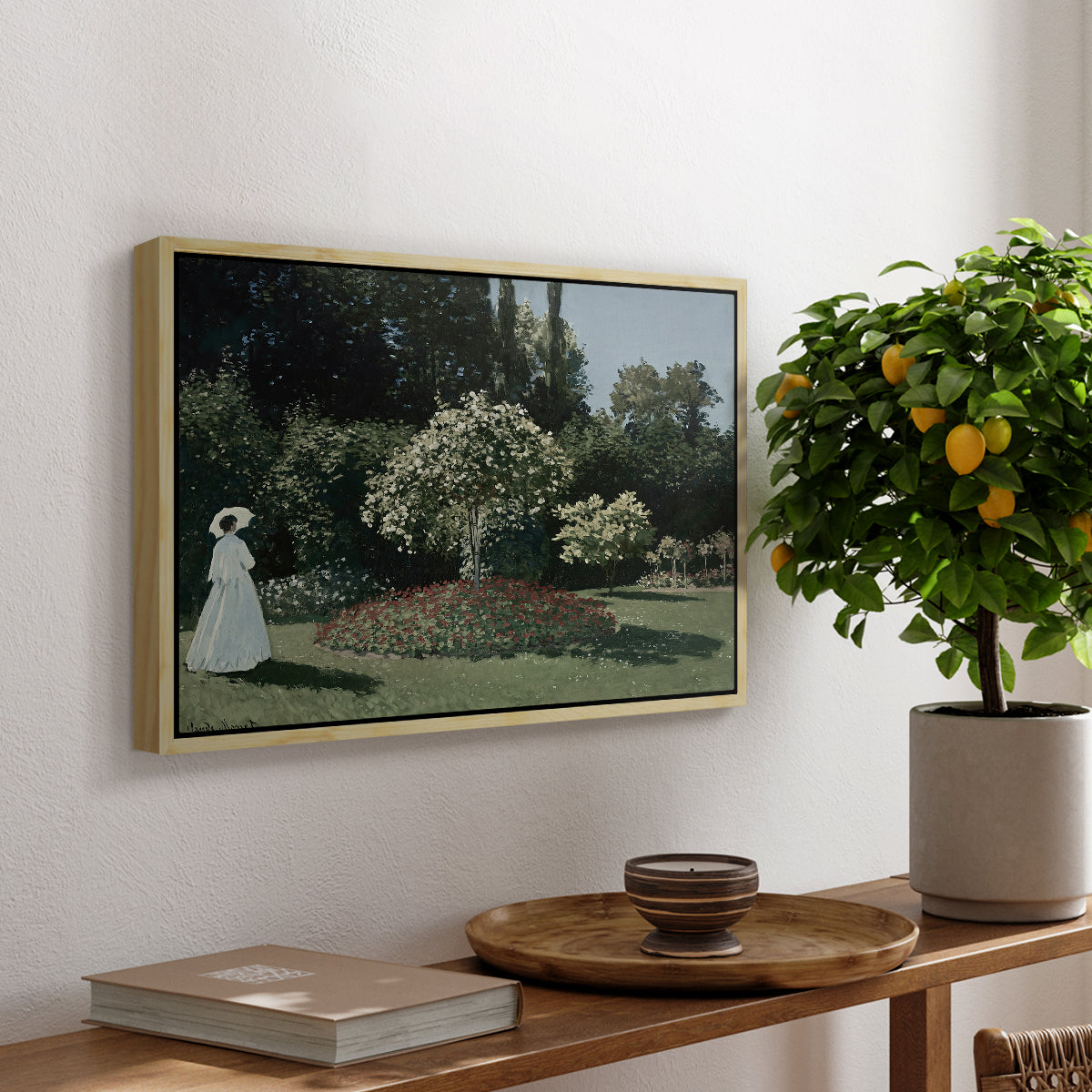 Woman in the Garden, Sainte-Adresse, 1867 by Claude Monet, presented in a natural wood floater framed canvas featuring a woman standing in garden surrounded by flowers and greenery, displayed above a hallway console table.