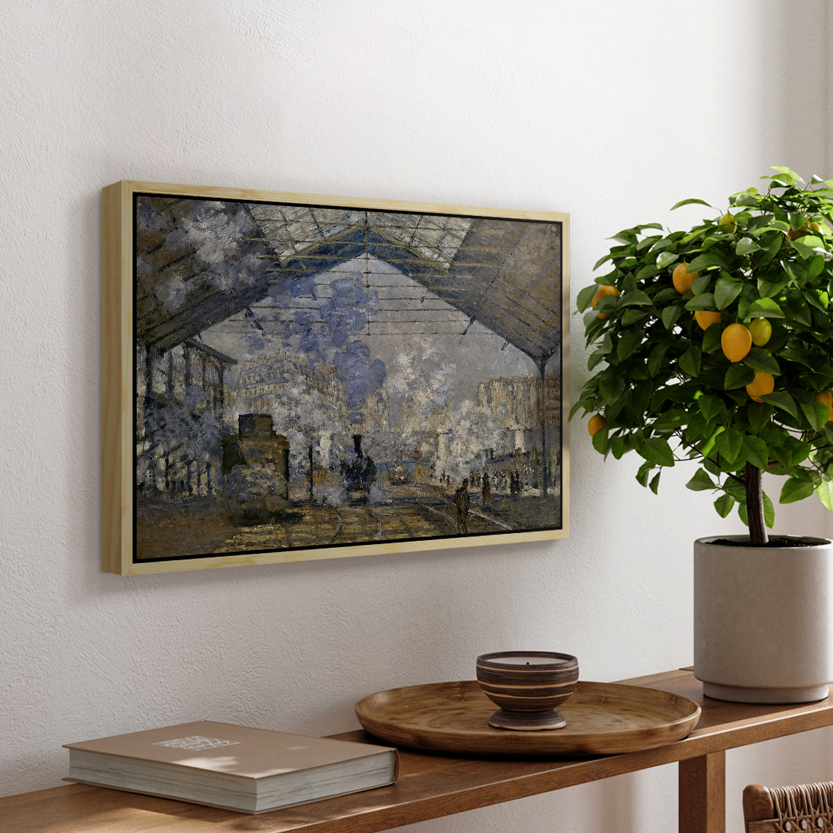 The Gare Saint-Lazare, 1877 by Claude Monet, presented in a natural wood floater framed canvas featuring a train station interior filled with steam and locomotives under iron structure, displayed above a hallway console table.