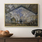The Gare Saint-Lazare, 1877 by Claude Monet in a natural wood floater framed canvas displayed above a console table in a hallway, featuring a bustling transport hub with trains beneath glass roof.
