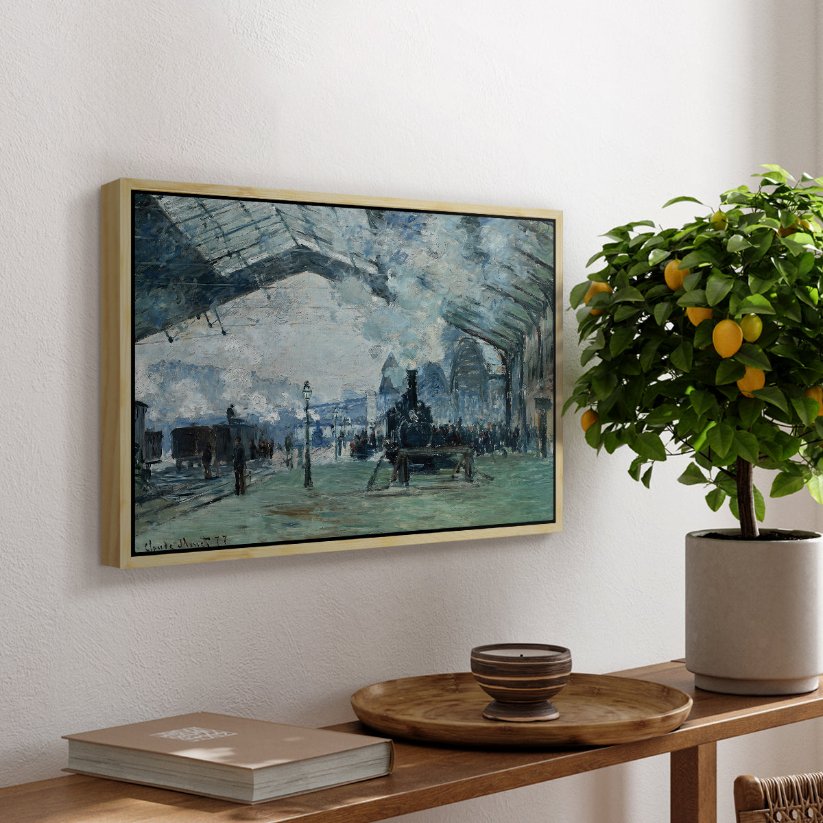 The Saint-Lazare Station, 1877 by Claude Monet, presented in a natural wood floater framed canvas featuring trains arriving under large arched station roof with billowing steam, displayed above a hallway console table.