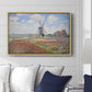 Tulip Fields with the Rijnsburg Windmill, 1886 by Claude Monet displayed above a sofa in a living room in a natural wood floater frame, featuring a vibrant agricultural landscape with flowers and windmill.