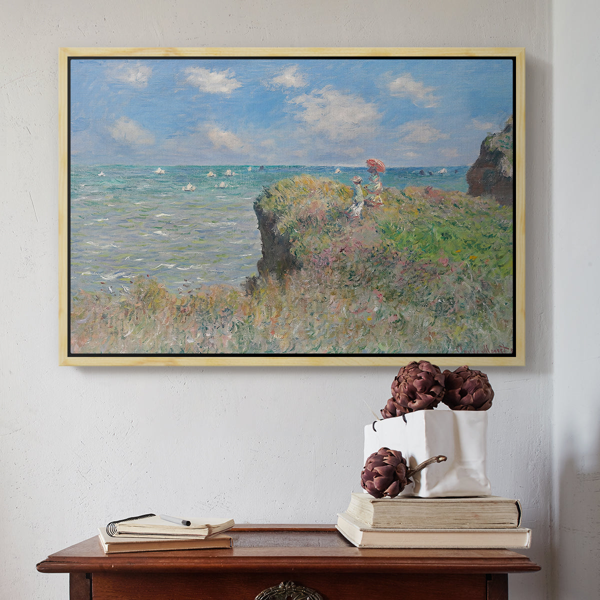 Natural wood floater framed canvas featuring The Cliff Walk at Pourville, 1882 by Claude Monet above an entryway table in a minimalist foyer.