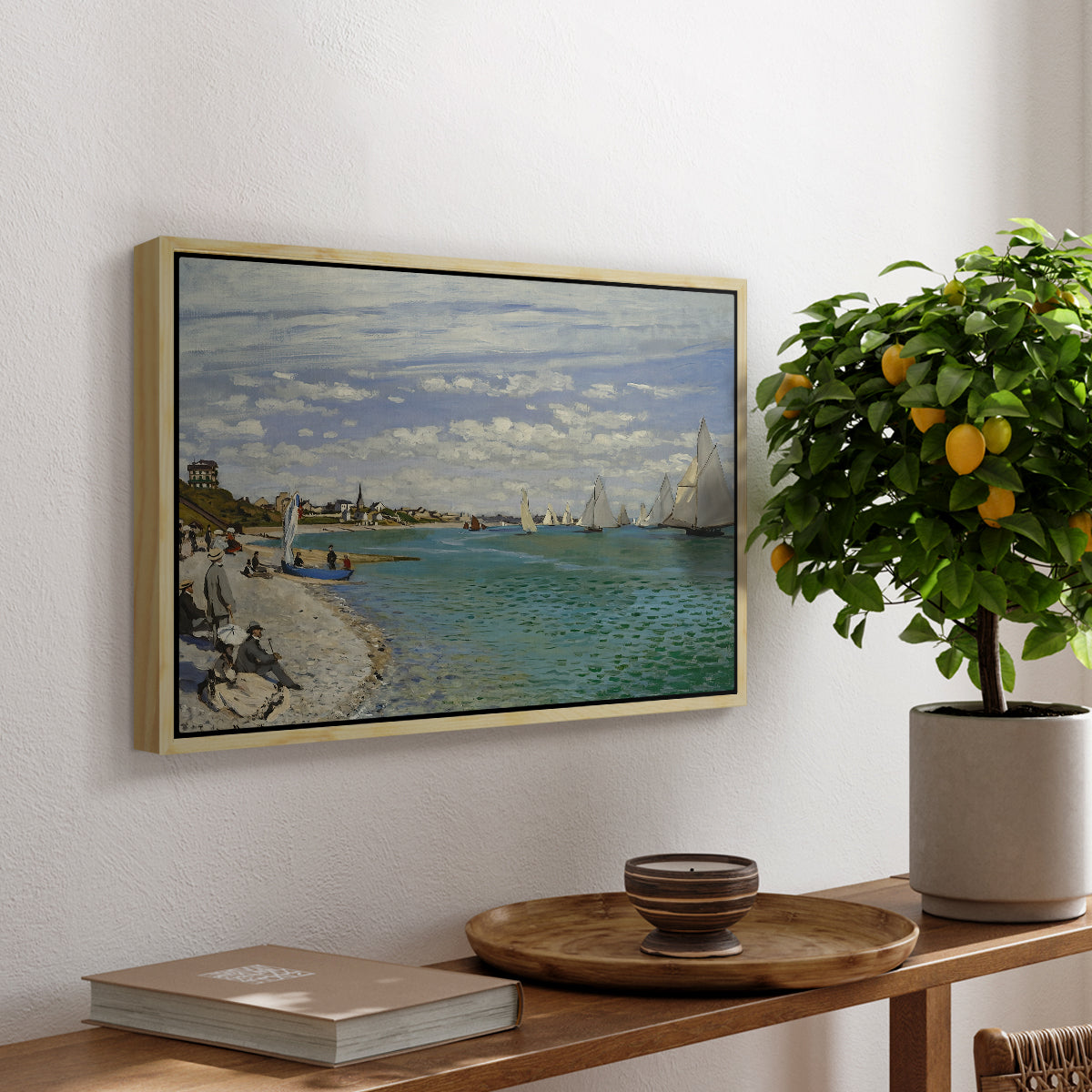 Regatta at Sainte-Adresse, 1867 by Claude Monet, presented in a natural wood floater framed canvas featuring sailboats gathered near shore with flags and spectators along coastline, displayed above a hallway console table.