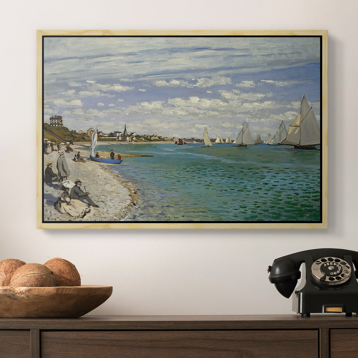 Regatta at Sainte-Adresse, 1867 by Claude Monet in a natural wood floater framed canvas displayed above a console table in a hallway, featuring a nautical scene with boats racing near seaside town.