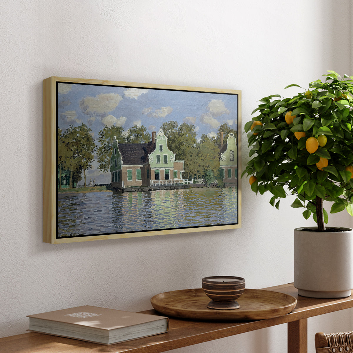 Houses on the Zaan River at Zaandam, 1871 by Claude Monet, presented in a natural wood floater framed canvas featuring a row of houses along river with reflections in calm water, displayed above a hallway console table.