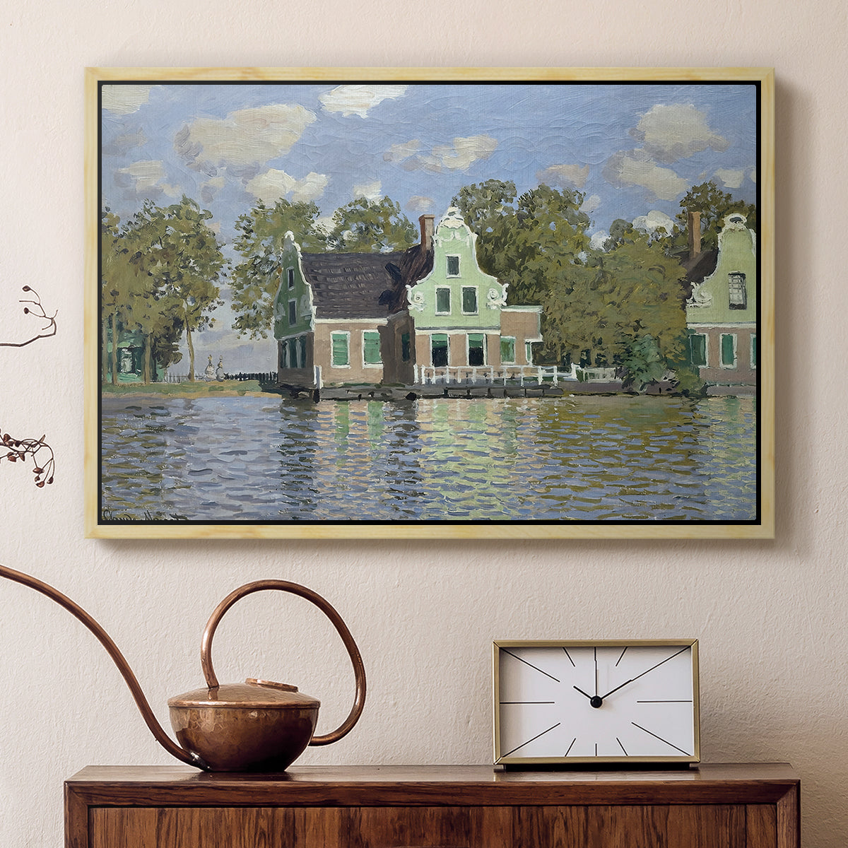 Natural wood floater framed canvas featuring a peaceful canal scene with houses mirrored in water, displayed above a cabinet in a soft-toned living room.