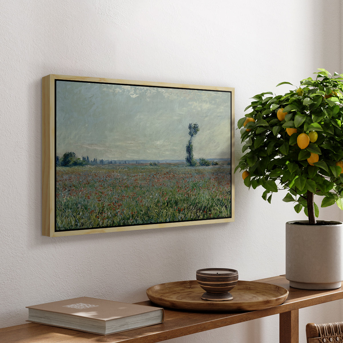 Poppy Field, 1881 by Claude Monet, presented in a natural wood floater framed canvas featuring a wide field of red poppies stretching across countryside under open sky, displayed above a hallway console table.