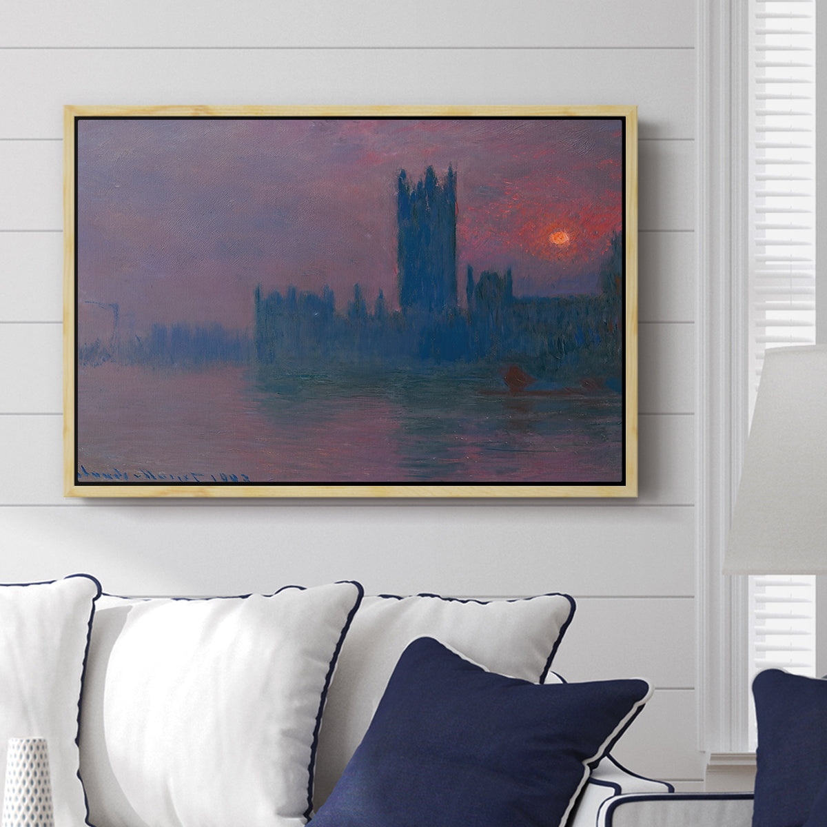 The Houses of Parliament, Sunset, 1903 by Claude Monet displayed above a sofa in a living room in a natural wood floater frame, featuring an impressionist cityscape with warm sunset light over water.