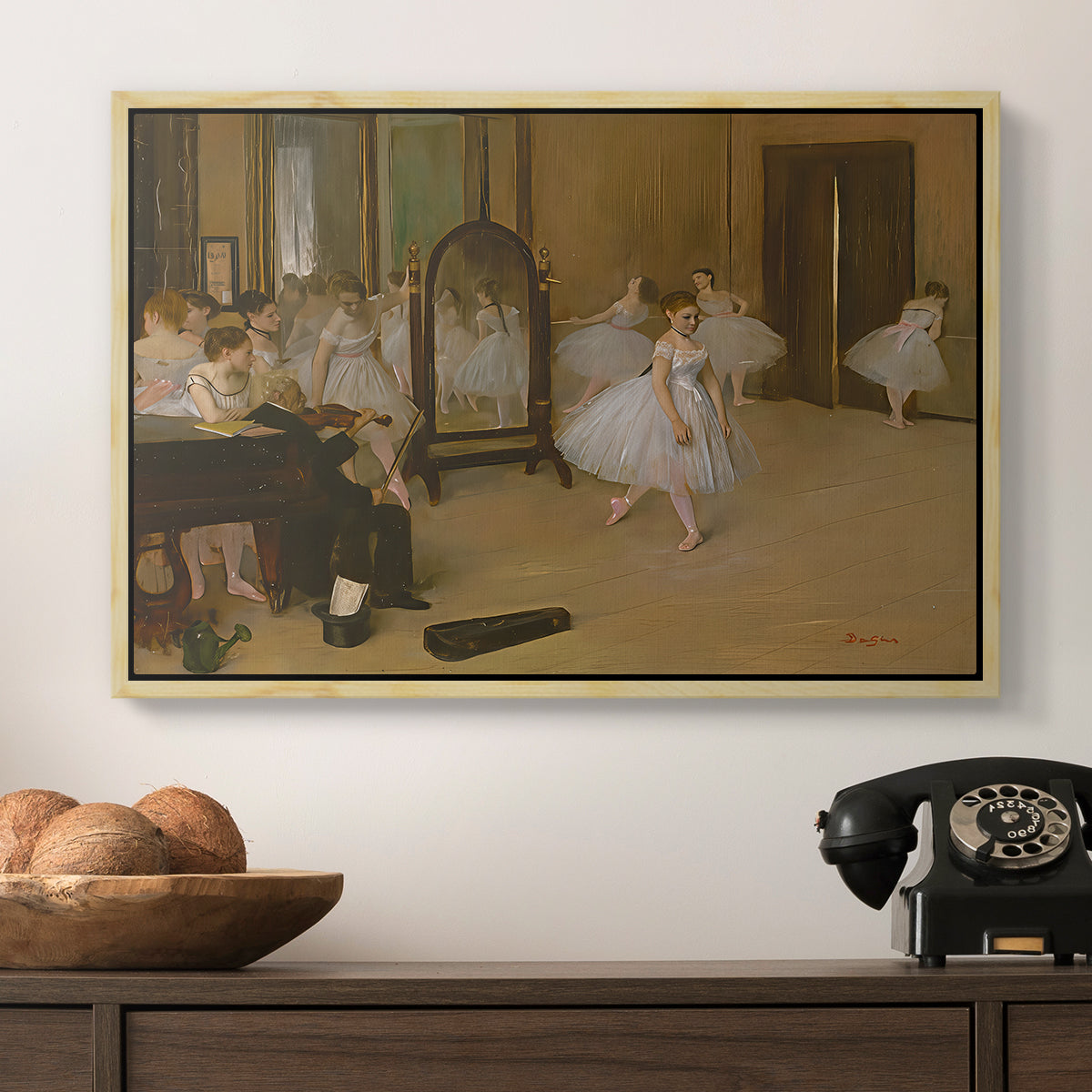 The Dancing Class, c. 1870 by Edgar Degas in a natural wood floater framed canvas displayed above a console table in a hallway, featuring a group of dancers mid-practice with teacher overseeing.
