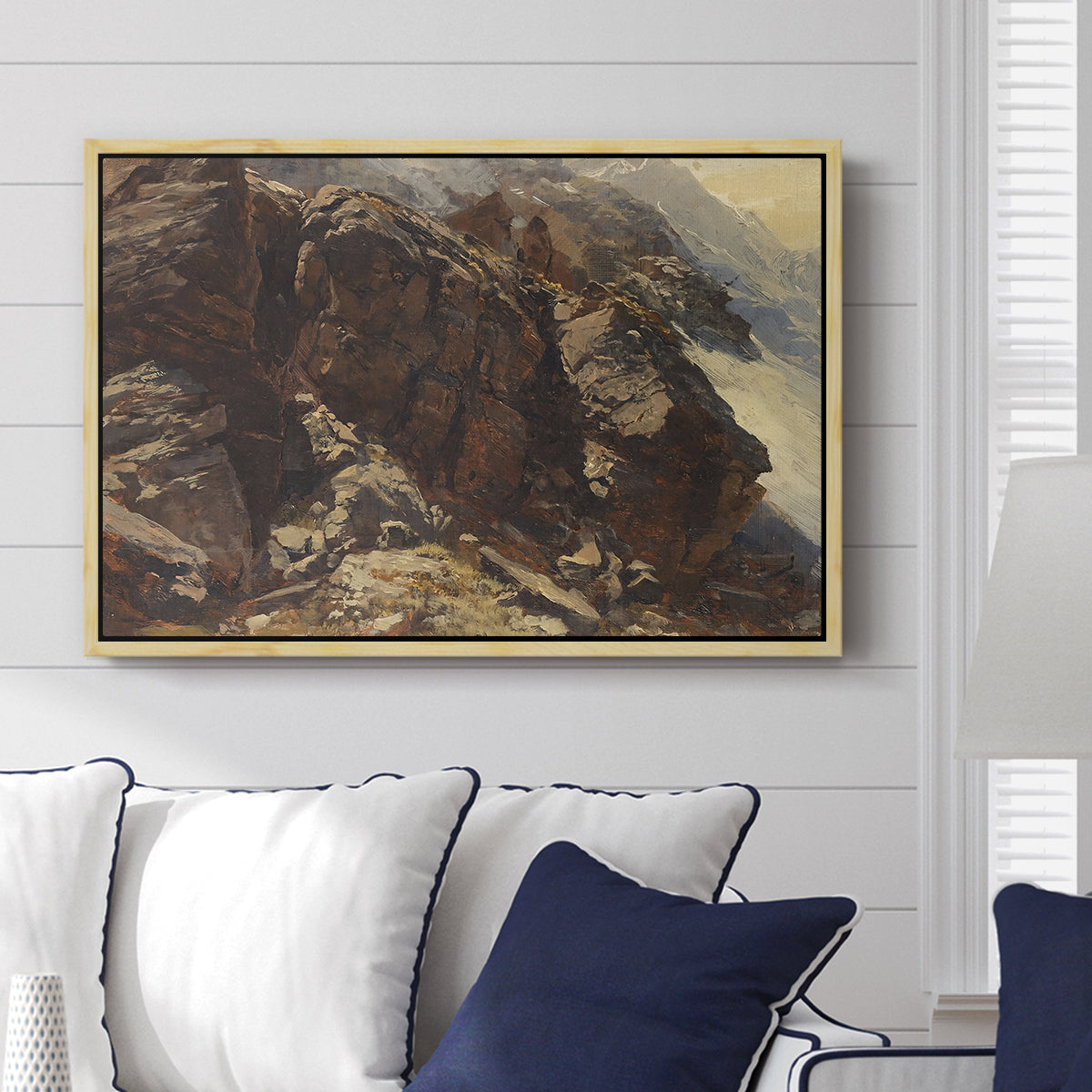 High Mountain Study, c. 1870 by Edward Theodore Compton displayed above a sofa in a living room in a natural wood floater frame, featuring a detailed study of rugged mountain landscape with sharp contours.