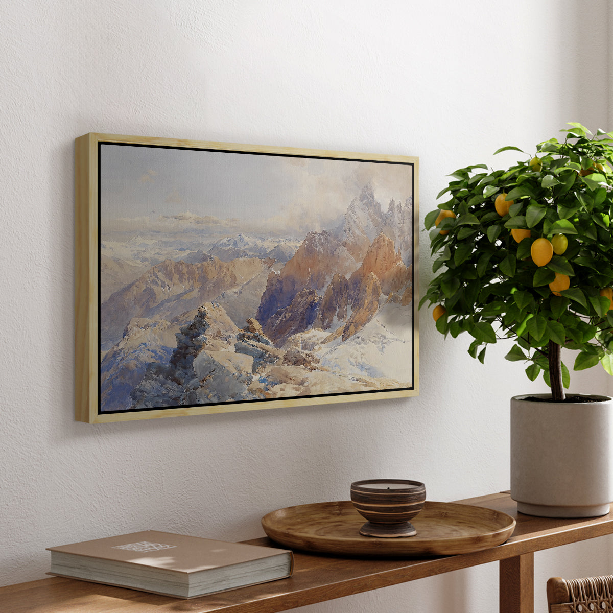 Col du Géant, 1903 by Edward Theodore Compton, presented in a natural wood floater framed canvas featuring a mountain pass with snow-covered peaks and expansive alpine valley, displayed above a hallway console table.